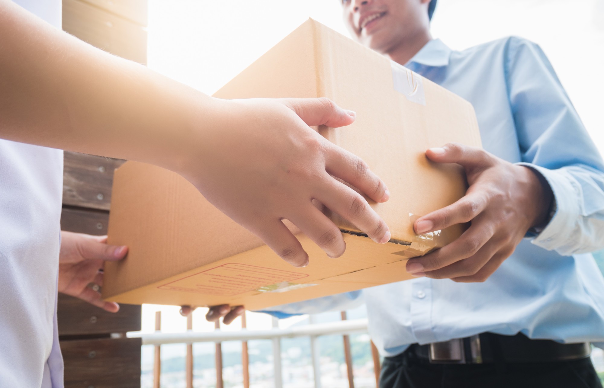 Hand of asia woman are receive a box from delivery man in delivery service concept